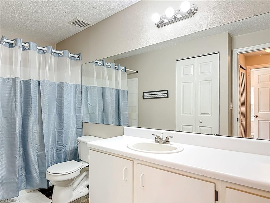 Bathroom featuring a textured ceiling, vanity, and a closet