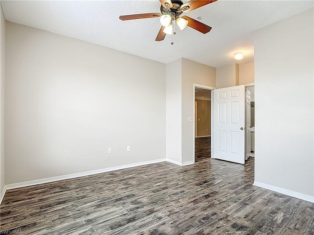 Spare room featuring dark wood-type flooring, ceiling fan, and a textured ceiling