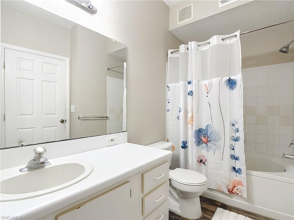 Bathroom with shower / tub combo, vanity, and dark wood finished floors