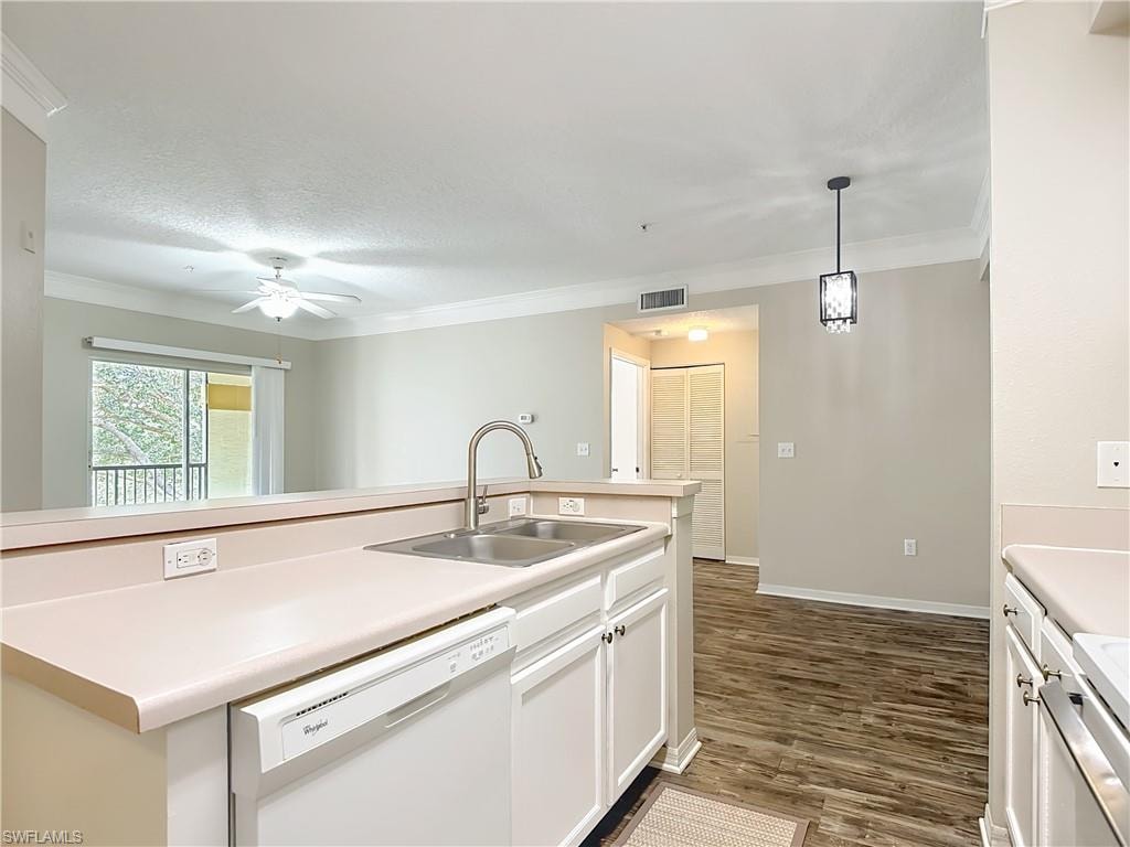 Kitchen with white dishwasher, light countertops, decorative light fixtures, white cabinets, and crown molding