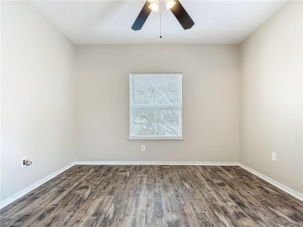 Spare room featuring dark wood-style floors, a ceiling fan, and a textured ceiling