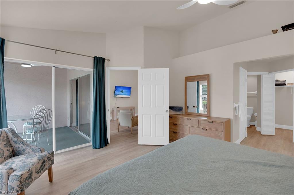 Primary bedroom featuring light wood-style floors, ceiling fan, access to exterior, and vaulted ceiling