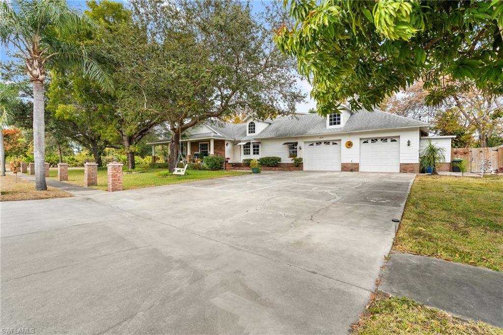 View of front of house featuring an attached garage, concrete driveway, a front lawn, and brick siding