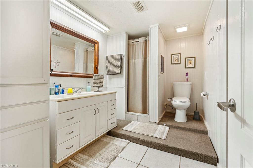Bathroom with curtained shower, vanity, light tile patterned floors, and ornamental molding