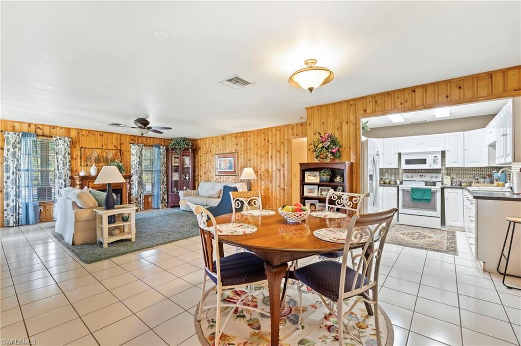 Dining space featuring a ceiling fan, wood walls, and light tile patterned floors