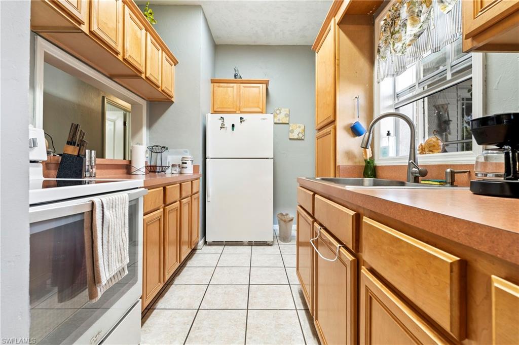Kitchen featuring white appliances, light tile patterned floors, and light countertops