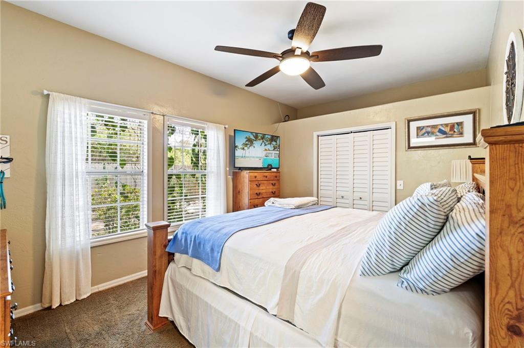 Bedroom with dark carpet, a closet, and ceiling fan