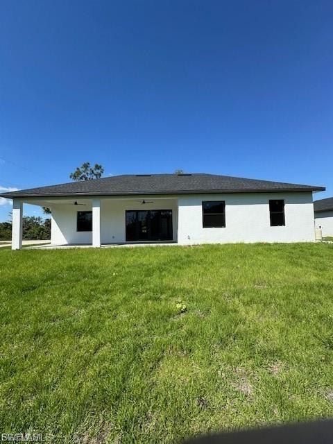 Rear view of house featuring a yard and stucco siding