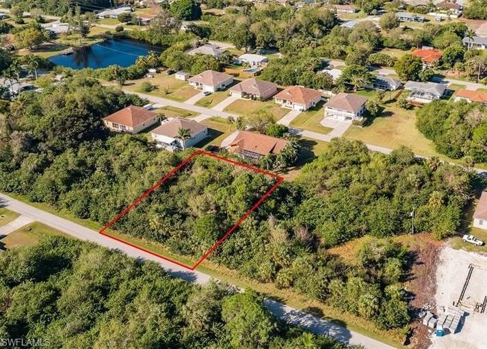 Aerial view of residential area with property boundaries highlighted and a large body of water