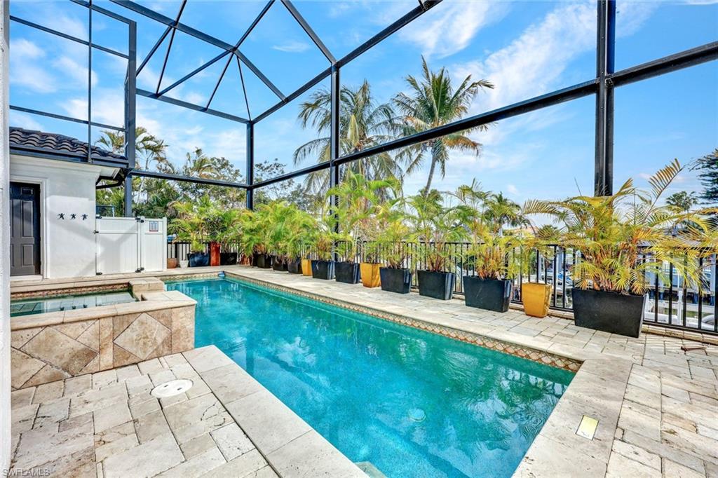 Integrated pool / spa with glass enclosure, a patio, and a sunroom