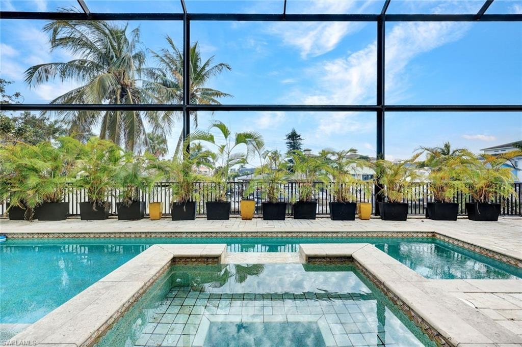 Integrated pool / hot tub featuring glass enclosure, a sunroom, and a patio area