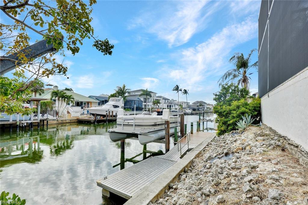 Dock featuring a water view, boat lift, and a residential view