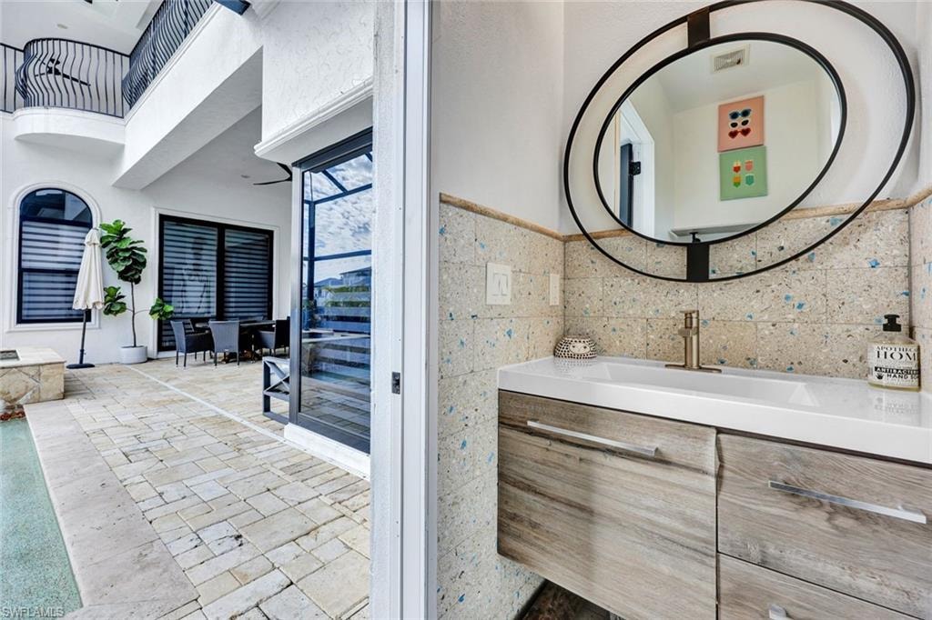 Bathroom featuring vanity, tile walls, and a high ceiling