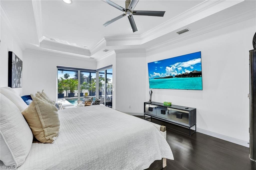 Bedroom with access to outside, a raised ceiling, dark wood-style flooring, ceiling fan, and ornamental molding
