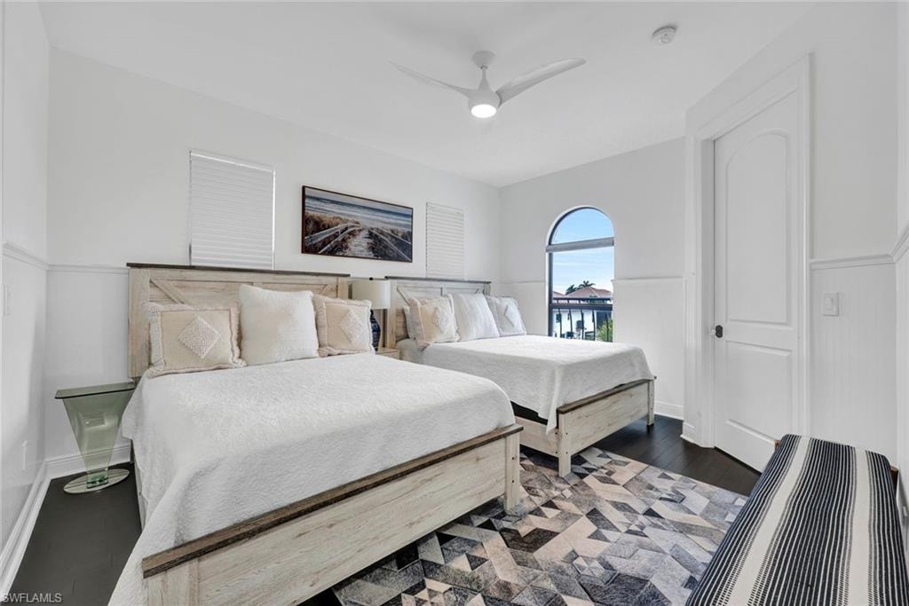 Bedroom featuring wood finished floors, ceiling fan, wainscoting, and access to exterior