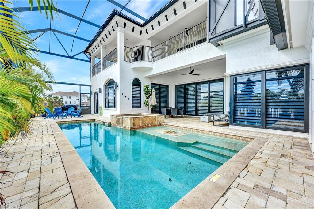 Integrated pool / spa featuring a balcony, a sunroom, a patio, outdoor dining space, and glass enclosure