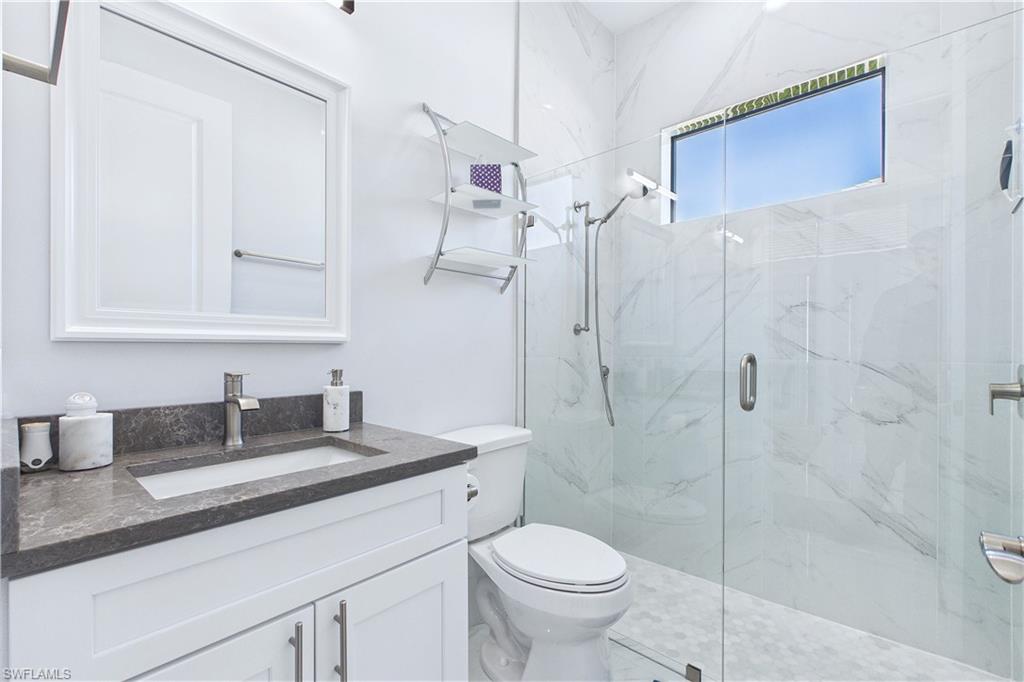 Full bathroom featuring a marble finish shower and vanity