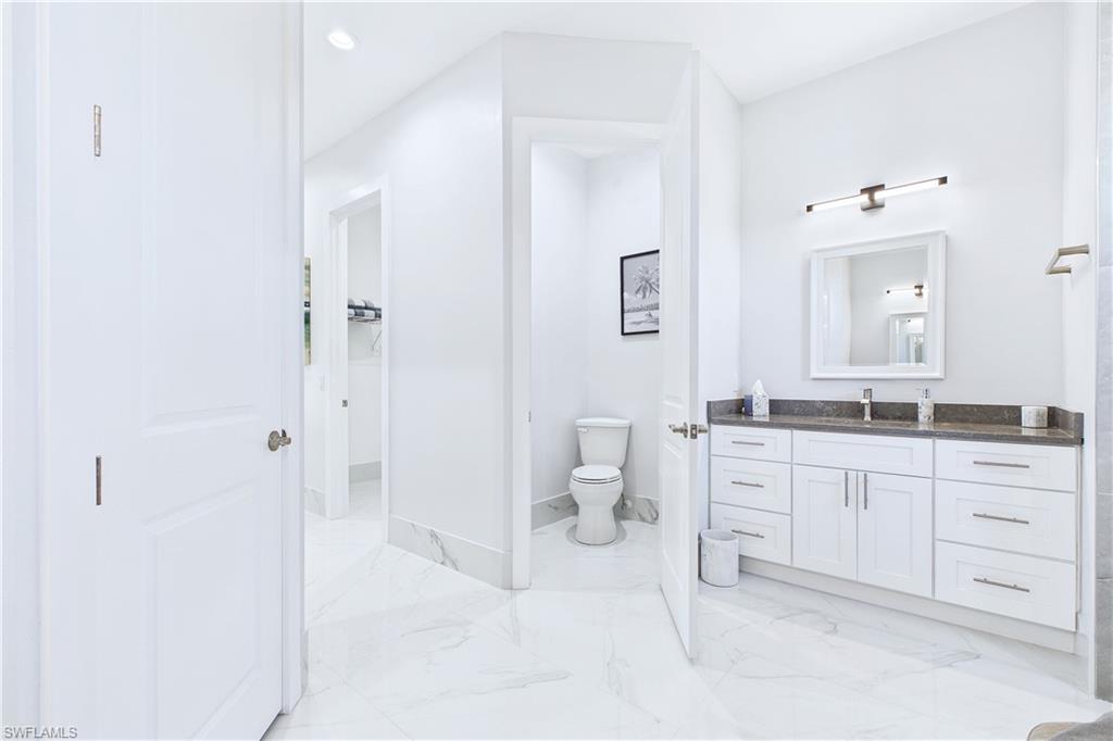Bathroom with vanity, light marble finish floors, and recessed lighting