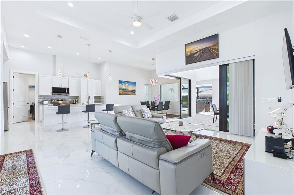 Living room with a raised ceiling, ceiling fan, and recessed lighting
