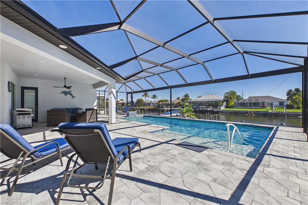 Swimming pool with a patio, glass enclosure, a sunroom, area for grilling, and a residential view