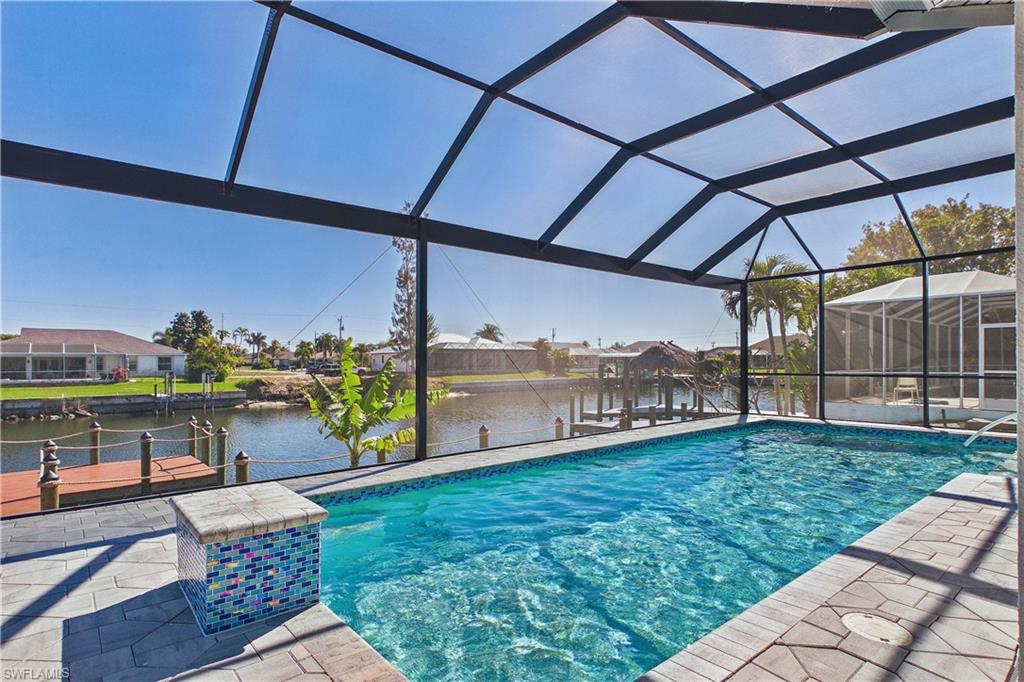 Swimming pool featuring glass enclosure, a dock, a water view, and a sunroom