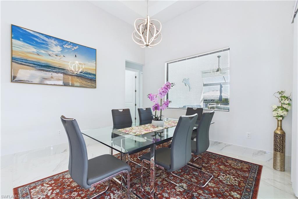 Dining space with marble finish flooring, a chandelier, and a high ceiling