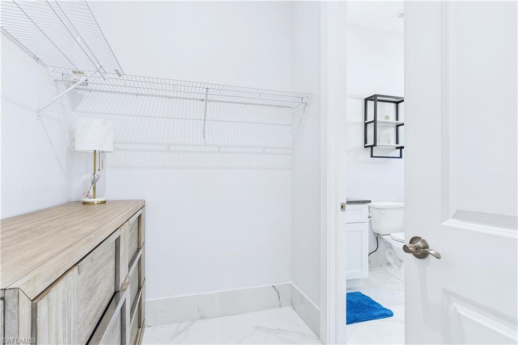 Walk in closet featuring light marble finish flooring