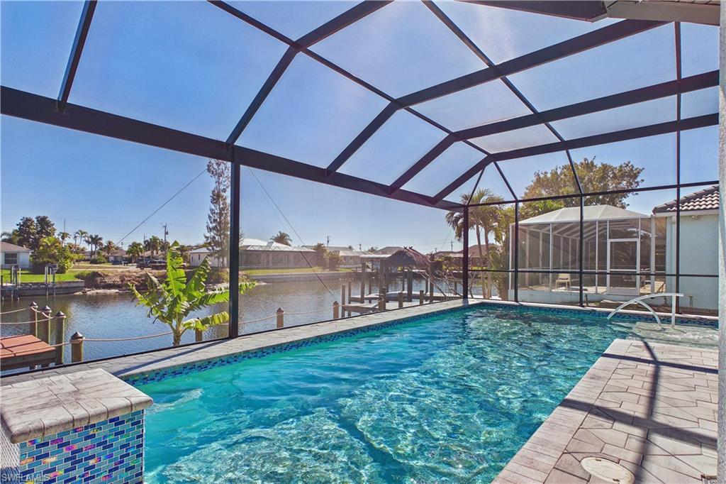 Outdoor pool with a lanai, a sunroom, a water view, a dock, and boat lift