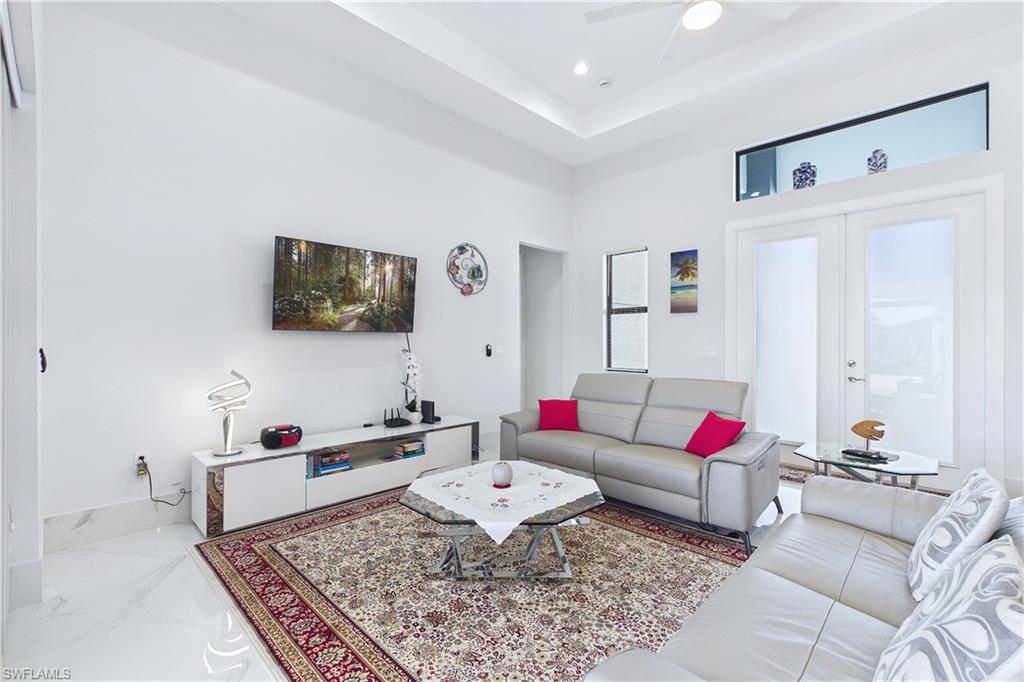 Living room featuring a raised ceiling, french doors, a ceiling fan, and recessed lighting