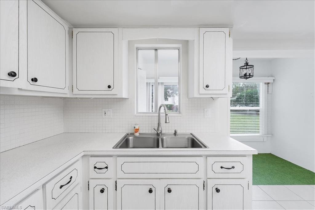 Kitchen with white appliances, light countertops, white cabinets, and tasteful backsplash