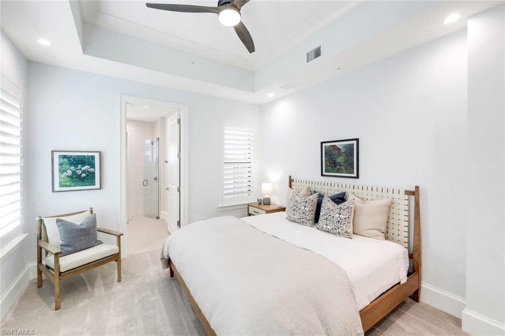 Bedroom featuring light colored carpet, recessed lighting, a ceiling fan, connected bathroom, and a tray ceiling