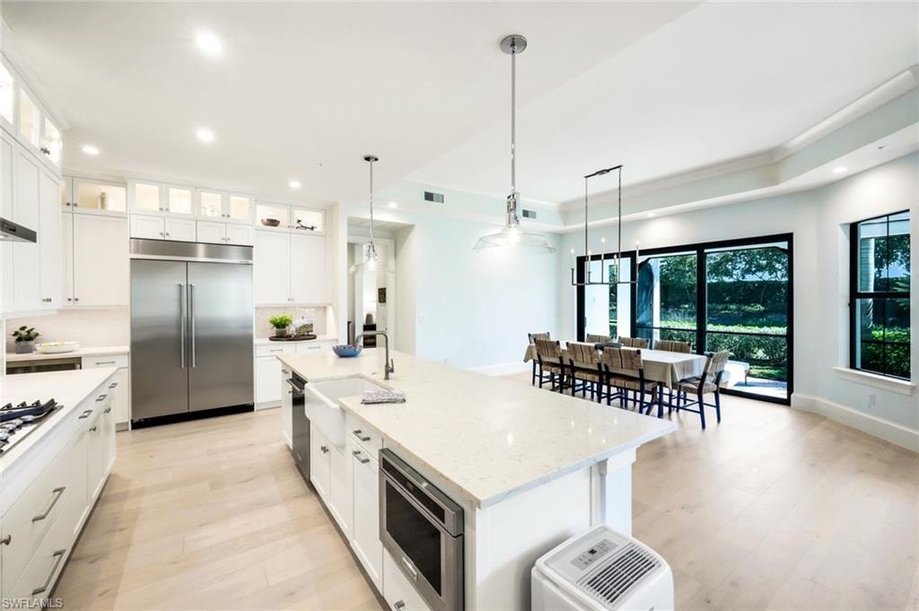 Kitchen featuring white cabinets, built in appliances, and light wood finished floors