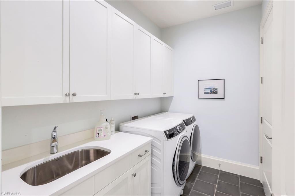 Laundry area with washer and dryer, cabinet space, and dark tile patterned floors