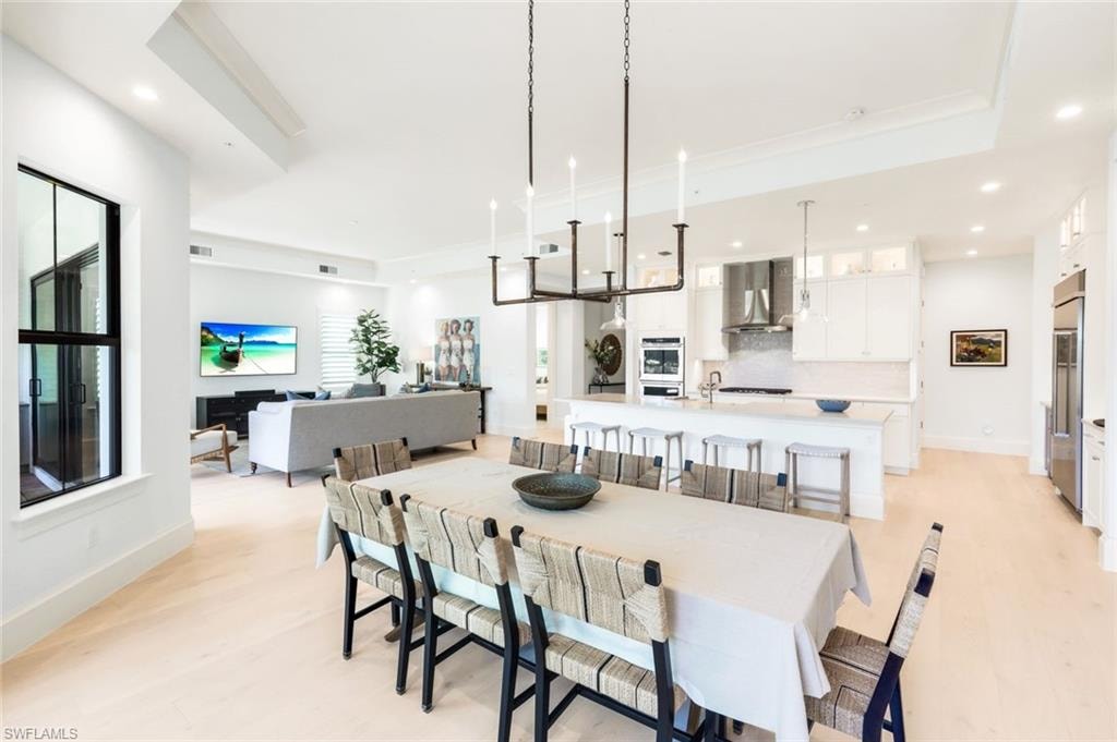 Dining space with recessed lighting, light wood-style floors, and a tray ceiling