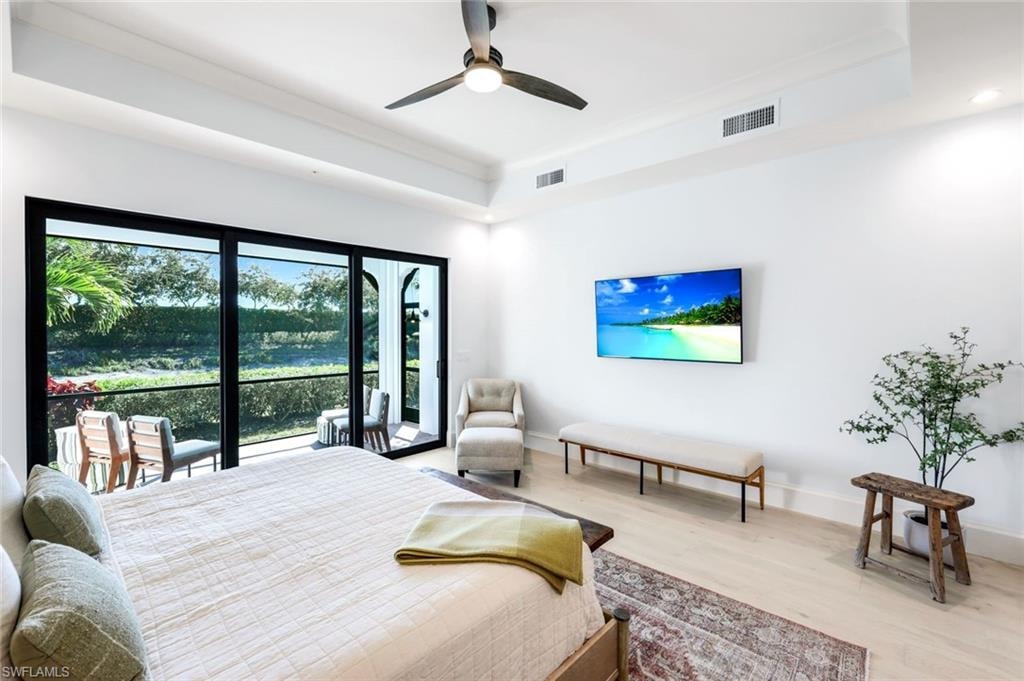 Bedroom with a raised ceiling, wood finished floors, a ceiling fan, and access to exterior