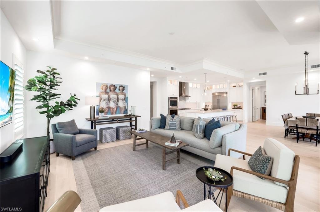 Living room featuring light wood-type flooring, a tray ceiling, and hanging lights