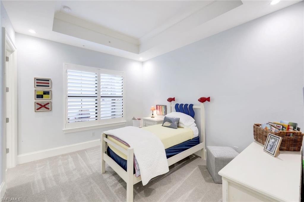 Bedroom with a raised ceiling, light carpet, and recessed lighting