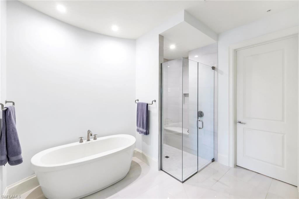 Full bathroom featuring a shower stall, a freestanding bath, light tile patterned floors, and recessed lighting