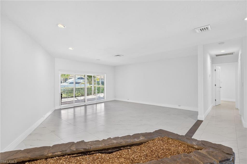 Empty room with light marble finish floors and recessed lighting