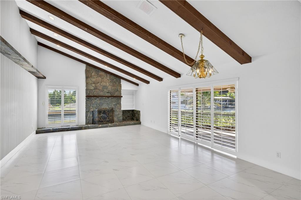 Unfurnished living room with lofted ceiling, a chandelier, and a fireplace