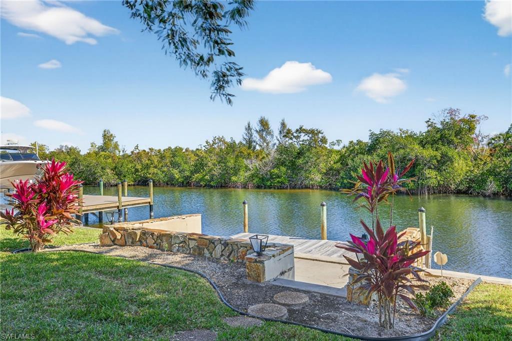 Dock area featuring a water view, a lawn, and view of wooded area
