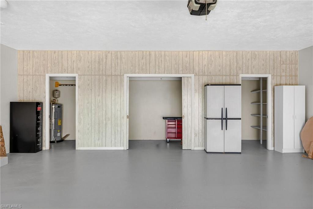 Garage with a garage door opener, wooden walls, and electric water heater