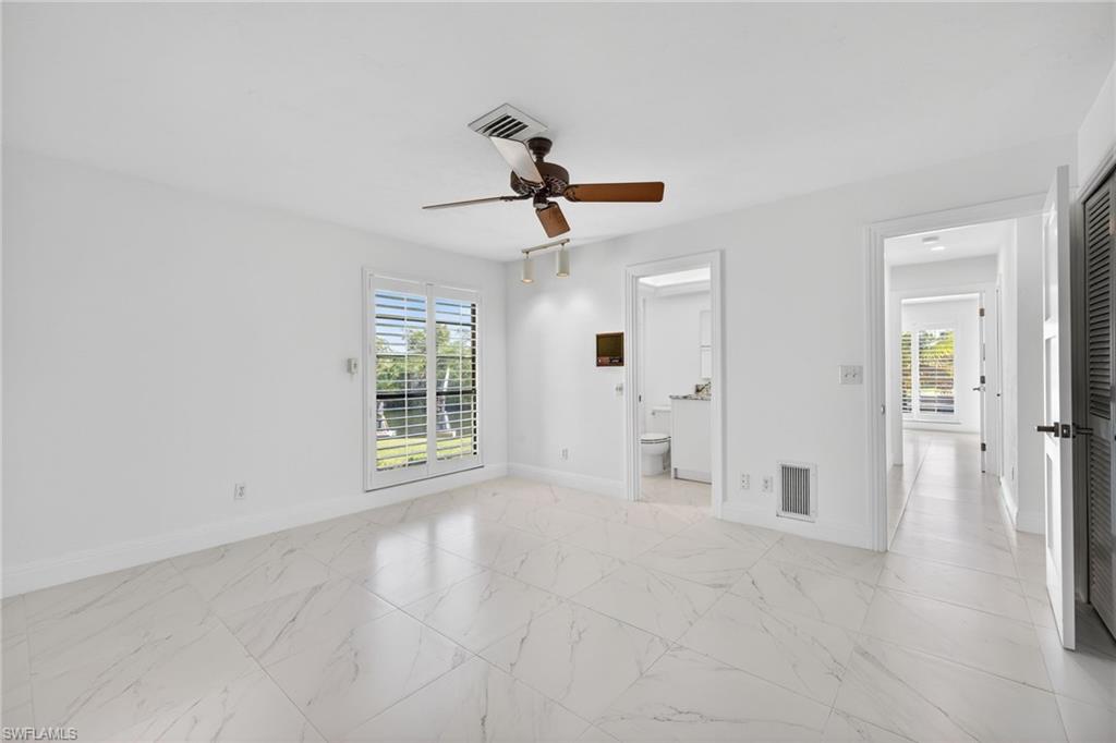 Unfurnished bedroom featuring multiple windows, ceiling fan, and light marble finish flooring