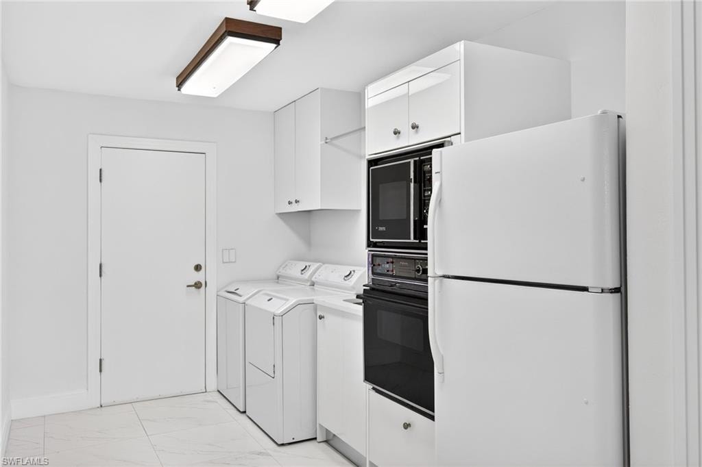 Kitchen featuring black appliances, white cabinets, light countertops, light marble finish flooring, and separate washer and dryer