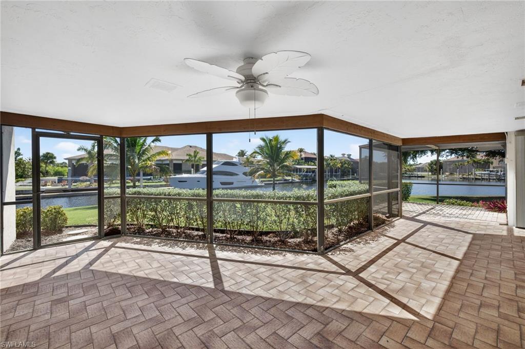 Unfurnished sunroom with a ceiling fan, a water view, and a patio area