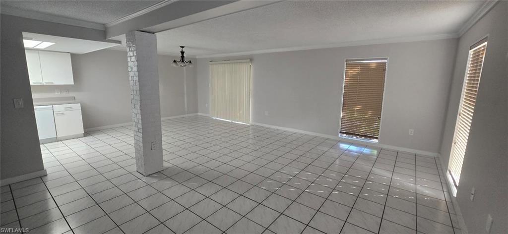 Unfurnished living room featuring a textured ceiling, crown molding, and light tile patterned flooring