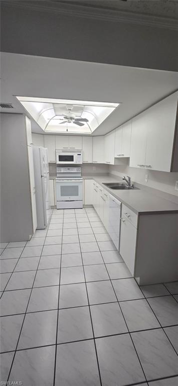 Kitchen featuring white appliances, white cabinetry, light tile patterned floors, and light countertops