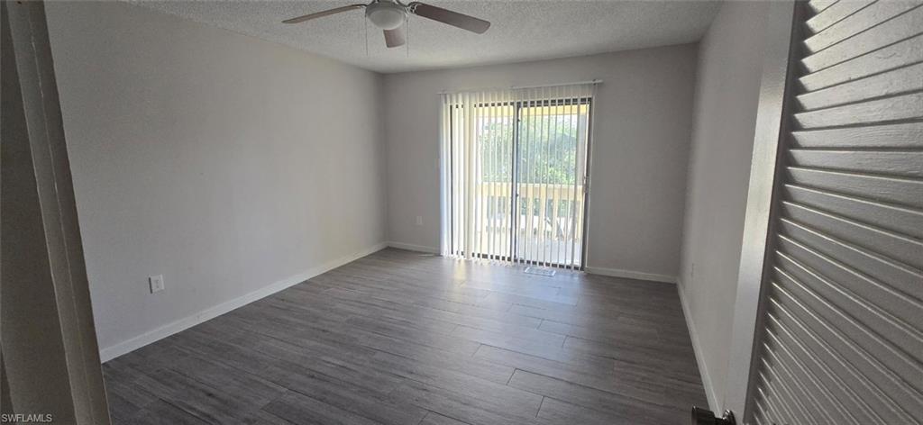 Unfurnished room with a textured ceiling, dark wood-type flooring, and a ceiling fan