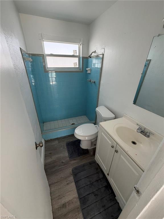 Full bath with a stall shower, vanity, and dark wood-style flooring