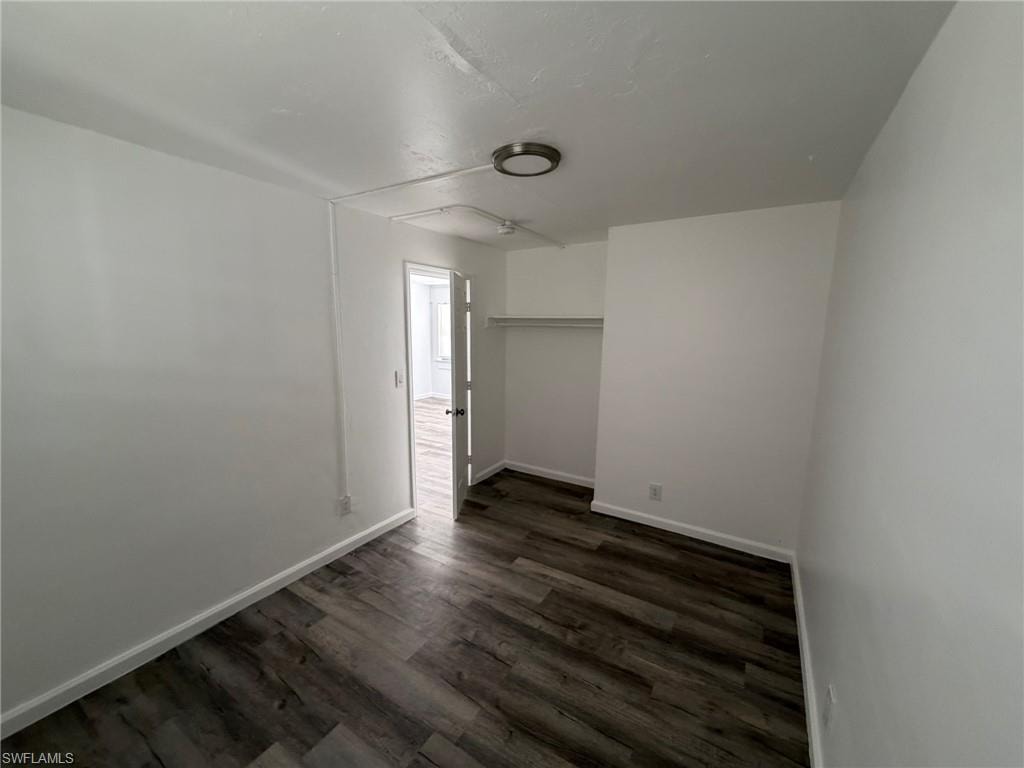 Unfurnished bedroom featuring dark wood finished floors and a closet